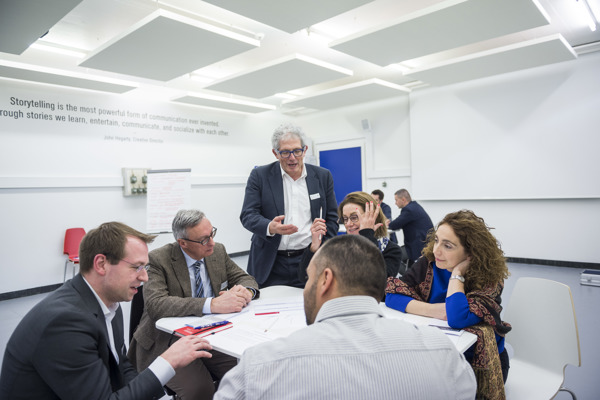 Groupe avec Professeur Groupe qui discutent autour d'une table accompagné du professeur