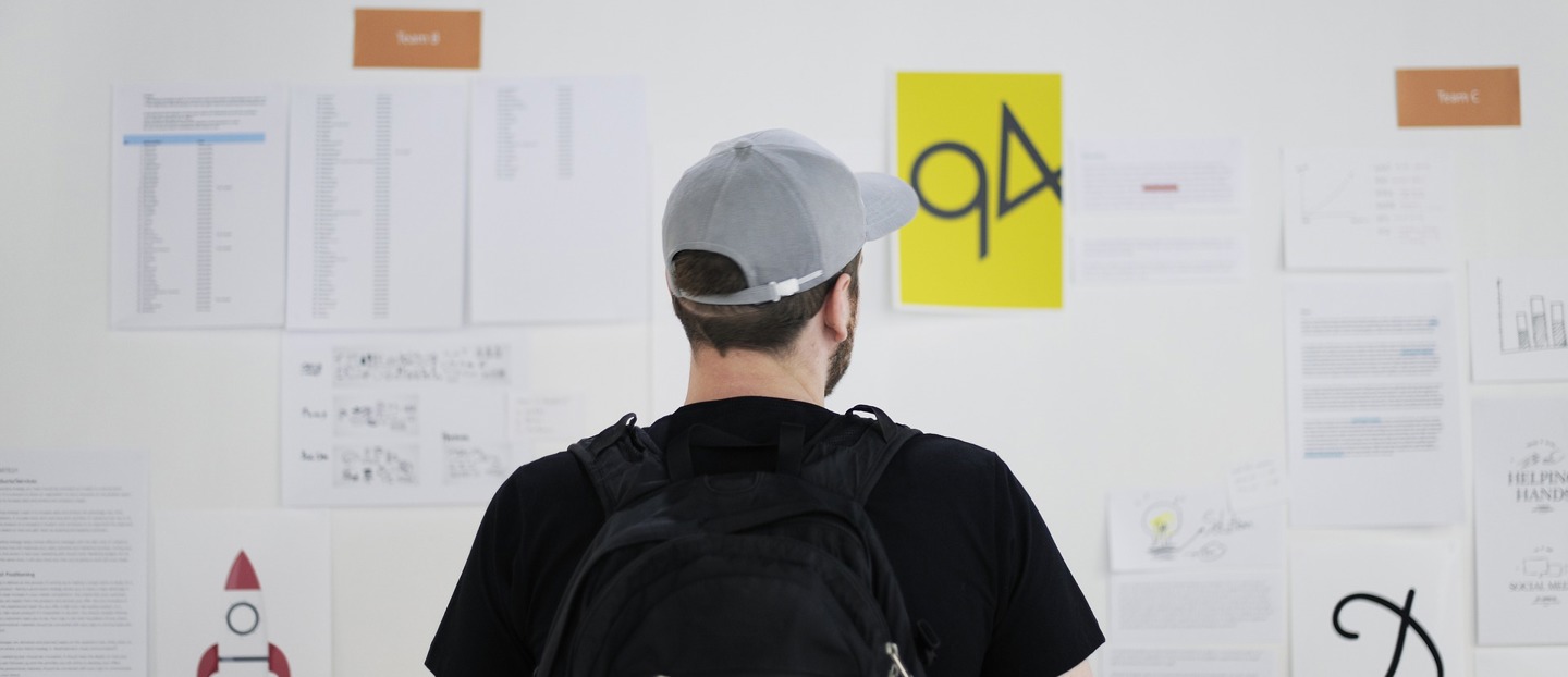 INSTITUT INNOVATION SOCIALE ET PUBLIQUE Une homme avec une casquette devant un tableau blanc rempli de feuilles