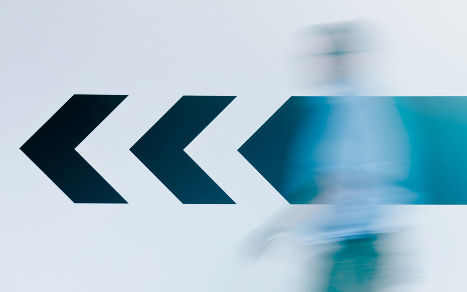 Flèche sur un mur de corridor avec une personne floutée 